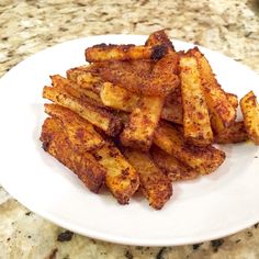 a white plate topped with french fries on top of a counter