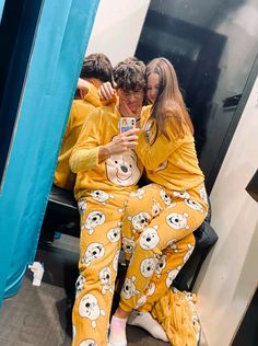 two people in matching yellow pajamas taking a selfie while sitting on a blue chair