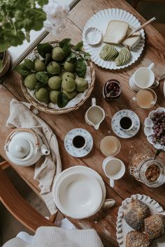 a wooden table topped with plates and cups filled with food