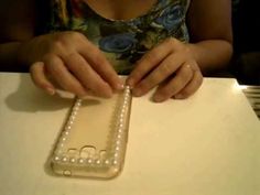 a woman sitting at a table with a cell phone in her hand and pearls on it