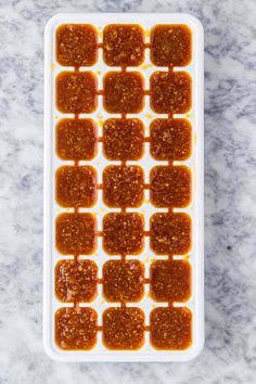 an ice tray filled with sauce on top of a marble counter