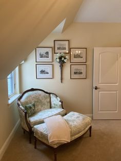 a chair and ottoman in a room with pictures hanging on the wall above it's door