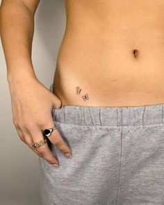 a woman's stomach with a small butterfly tattoo on her left side, and the bottom half of her abdomen visible