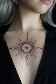 a woman's chest with a compass tattoo on her chest and the sun behind it