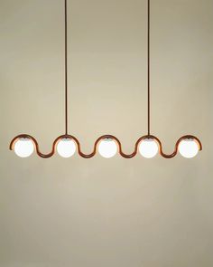 three lights hanging from the ceiling in a room with white walls and brown flooring