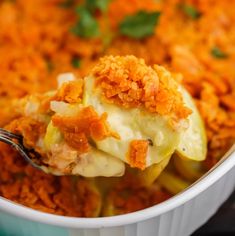 a spoon with some food in it on top of a white bowl filled with carrots