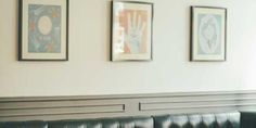 three framed pictures hang on the wall above a black leather couch in a restaurant setting