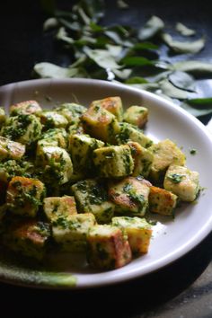 a white plate topped with tofu and broccoli on top of a table