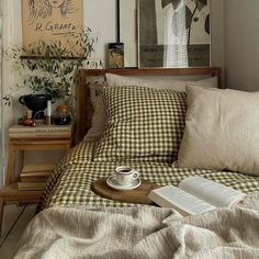 a coffee cup and book on a bed in a small room with an open window