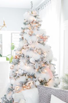 a white christmas tree with pink and silver ornaments