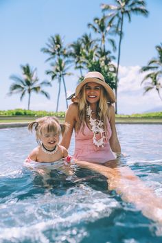 a woman and her child are in the water on surfboards with palm trees behind them