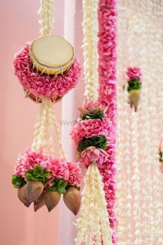 pink and white flowers are hanging from the ceiling next to a wall with an instrument on it