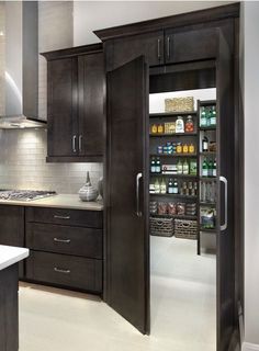 an open pantry in the middle of a kitchen with dark wood cabinets and white counter tops