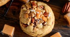 a chocolate chip cookie with pecans and nuts on top, surrounded by other cookies