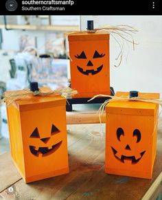 three pumpkin boxes with faces on them sitting on a wooden table in front of a store window