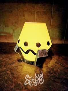 a yellow paper lantern sitting on top of a counter next to a wall with graffiti written on it