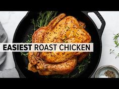 a roast chicken in a cast iron skillet with herbs and seasoning on the side