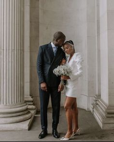 a man in a suit and tie standing next to a woman wearing a white dress