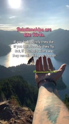 someone holding their hand up to the sky with mountains in the background and a bird flying over them