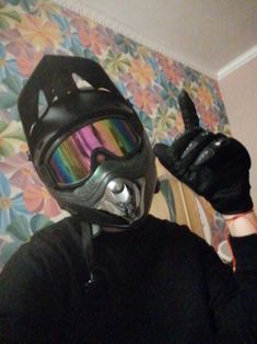 a person wearing a motorcycle helmet and goggles holds up their hand to the camera