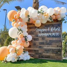 a sign with balloons and greenery on it