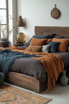 Minimalist wooden bed with dark stains and layered bedding in a cozy room. Navy Bedding Boho, Romantic Earthy Bedroom, Master Bed Color Schemes, Grey Bedspread Room Ideas, Boho Moody Bedroom, Gray Bedspread Room Ideas, Earthy Moody Bedroom, Navy And Rust Bedroom, Boho Bedroom Colors