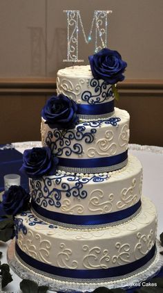 a wedding cake with blue roses and the initials m and n on top is displayed