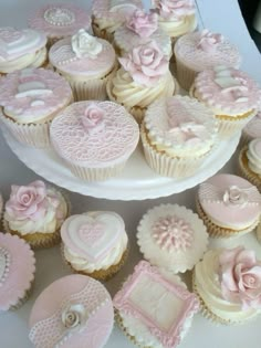 cupcakes decorated with pink and white frosting on a cake plate, surrounded by other decorations