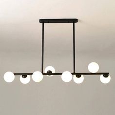 an overhead light fixture with five white balls hanging from it's center and four black bars