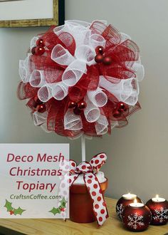 a red and white mesh christmas wreath on top of a wooden table with decorations around it