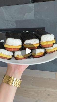 a person holding a white plate with food on it and gold bracelets around their wrist