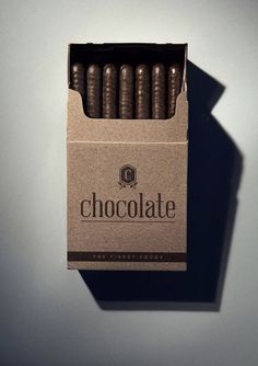 an open box of chocolate cigars sitting on a table next to a white wall