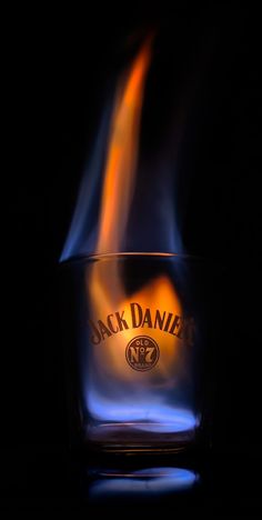 a glass filled with liquid sitting on top of a black table next to a lit candle