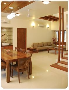 a dining room table and chairs in front of a living room with stairs leading up to the second floor