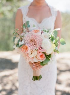 a bride holding a bouquet of pink and white flowers