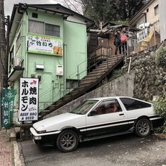 a car parked in front of a green building with stairs leading up to the top