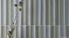 a vase filled with flowers sitting on top of a table next to a tiled wall