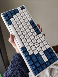 a person holding up a blue and white keyboard