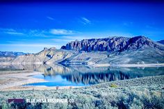 a lake surrounded by mountains and grass with the words blue mesa national park written on it