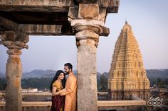 a man and woman standing next to each other in front of a building with many spires