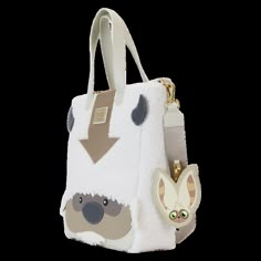 a white purse with a dog and cat on it's side, sitting next to a keychain