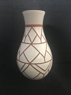 a white and brown vase sitting on top of a table