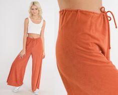 "Vintage 70s pants in burnt orange velour with a high drawstring waist and a wide leg.  Please see measurements and condition below. Every garment we sell is authentic vintage and one-of-a-kind! You will receive the exact item photographed. Condition: Very good vintage with light general wear. Best fits women's: Medium  Tag: hug me too Material:  velour MEASUREMENTS Taken from seam to seam while the garment is lying flat. Double the armpit, waist, and hips For reference, model is 5'8\" and measu Orange Drawstring Bottoms For Loungewear, 70s Pants, Patch Pants, Velour Pants, Punk Pins, Punk Patches, Boho Festival, Boho Hippie, Palazzo Pants