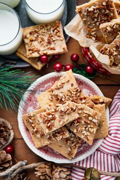 homemade christmas crackers on a plate next to candles and pine cones with holly wreaths