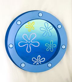 a blue metal plate with flowers painted on the front and sides, sitting on a white surface