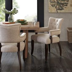 a dining room table and chairs in front of a window with a painting on the wall