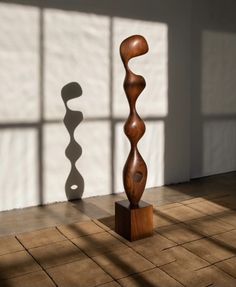 two wooden sculptures sitting on top of a tile floor in front of a large window