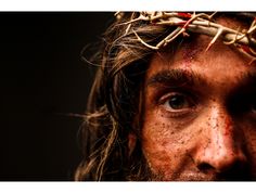 a close up of a man's face wearing a crown of branches on his head