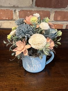 a blue mug filled with flowers on top of a wooden table