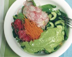 a white bowl filled with veggies on top of a blue and green table cloth